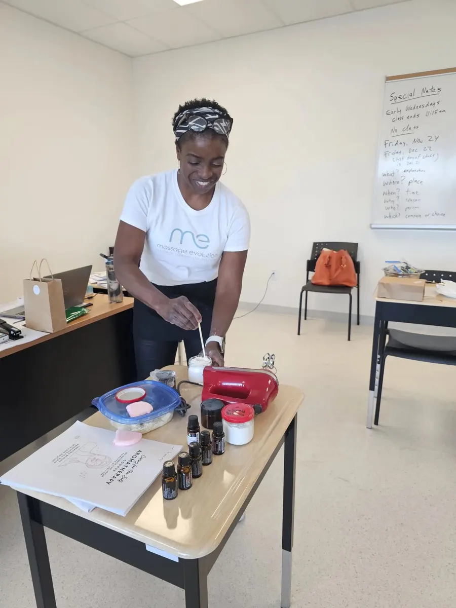 Ayanna at a table of essential oils and supplies, teaching a class on making body care products